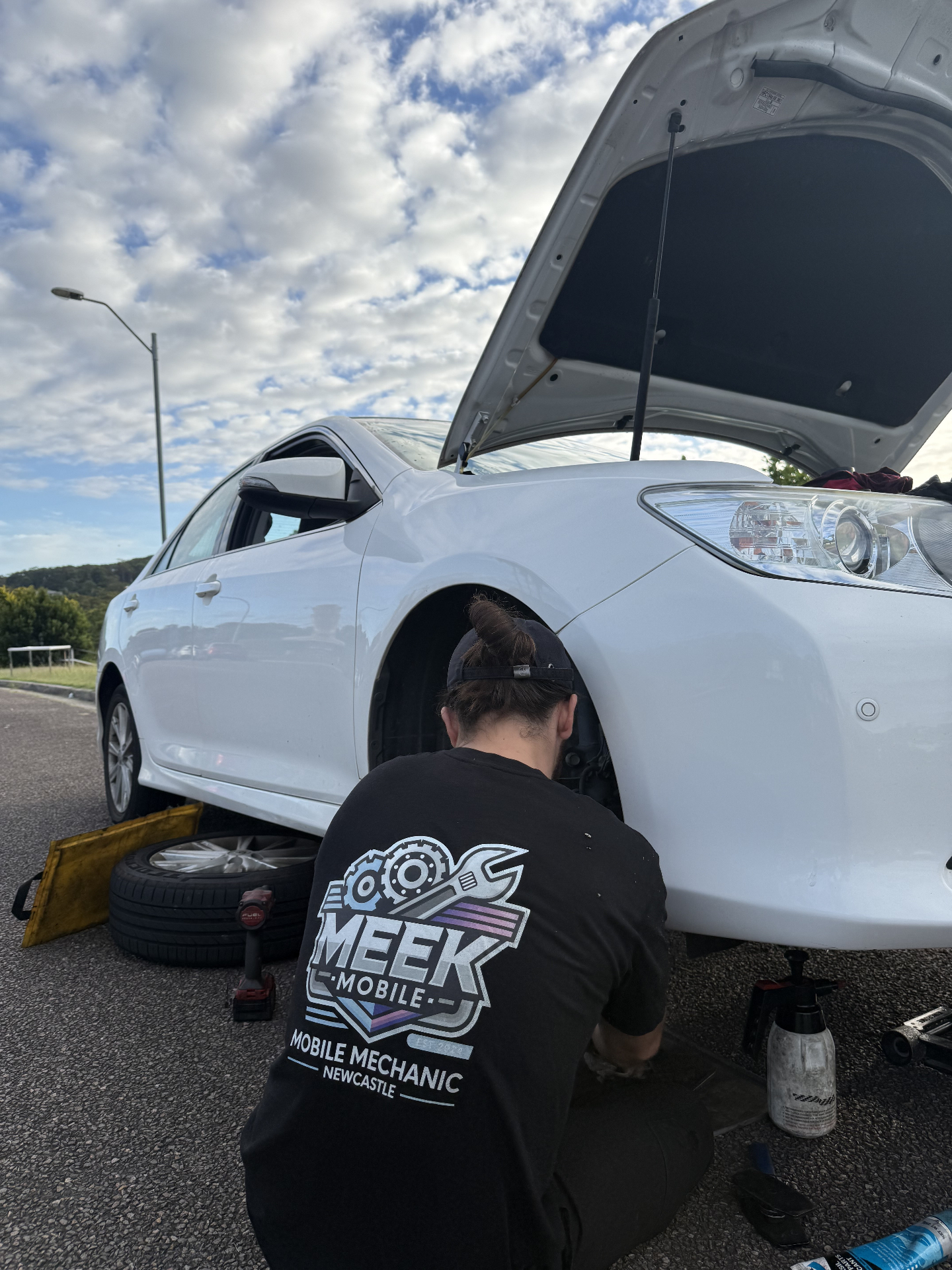 Mobile mechanic servicing a white sedan on a driveway - Meek Mobile, Newcastle